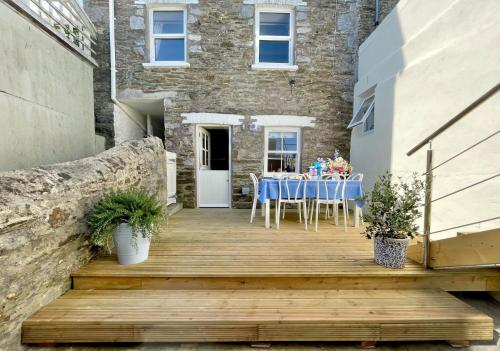 a wooden deck with a table and chairs on it at Enchanting Harbourside Cottage with Panoramic Views in Polruan