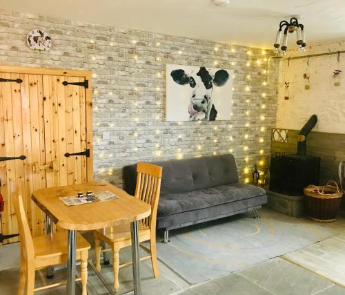uma sala de estar com um sofá e uma mesa em The Cuddly Cow Cosy Barn Studio Farm Stay em Dunmuckrum