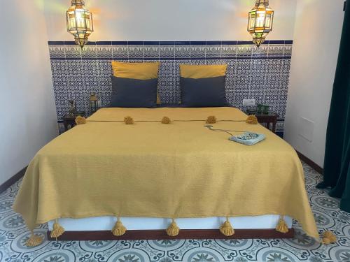 een slaapkamer met een groot bed met een gele sprei bij Kasbah Andaluz guest house in Chiclana de la Frontera
