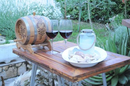 a table with two glasses of wine and a vase at Little house Kućica in Banjol