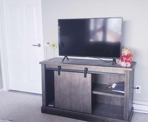 a flat screen tv on a wooden entertainment center at Calgary Gorgeous Single House close LRT&UC&Free Parking in Calgary
