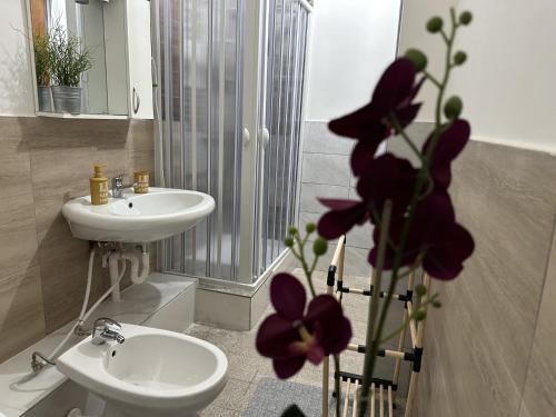 a bathroom with a sink and a toilet and flowers at Le stanze di Regina Margherita in Palermo
