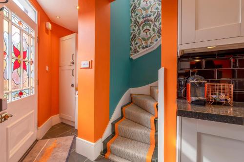 a hallway with orange and blue walls and stairs at Luxury Central Home - Parking & EV point, Superking bed in Canterbury