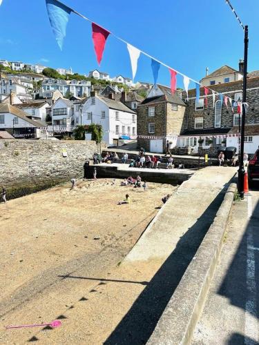a beach with flags and people sitting on the sand at Enchanting Harbourside Cottage with Panoramic Views in Polruan