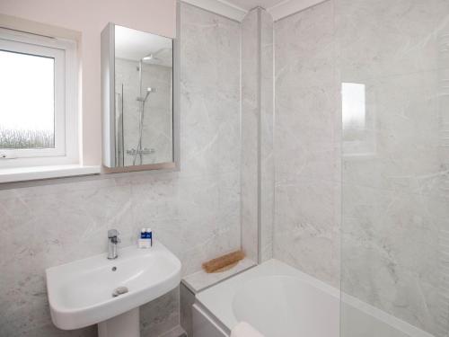 a white bathroom with a sink and a shower at Gatekeepers Cottage - Uk6728 in Lydstep