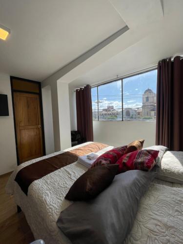 a bedroom with a bed and a large window at Suite Hotel Olimpico in Huancayo