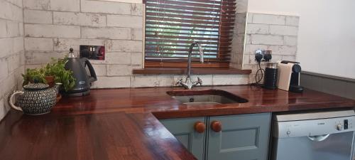 uma cozinha com um lavatório e uma bancada de madeira em The Stables em Skibbereen