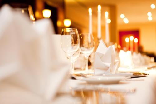a table with wine glasses and plates on it at Vienna House by Wyndham Thüringer Hof Eisenach in Eisenach