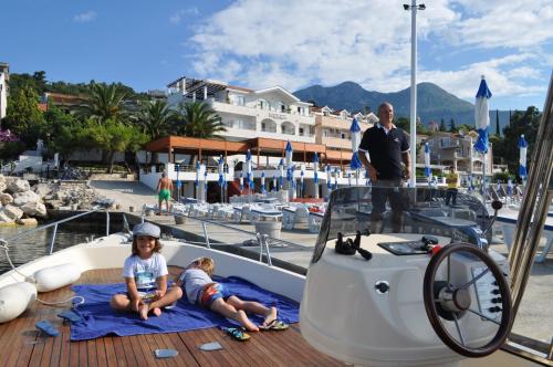 two children sitting on the deck of a boat at Hotel Perla in Herceg-Novi