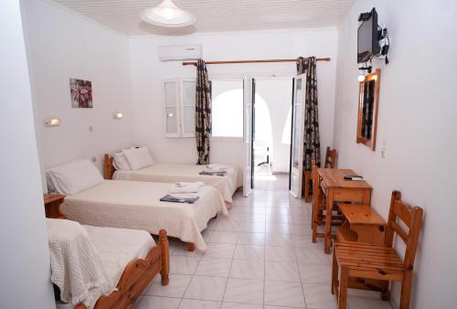 a room with two beds and a table and chairs at Kostas Beach Apartments in Agios Gordios