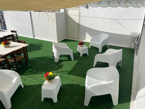 a room with white chairs and tables and flowers at "L'Oasi di Favignana" Room and Charme in Favignana