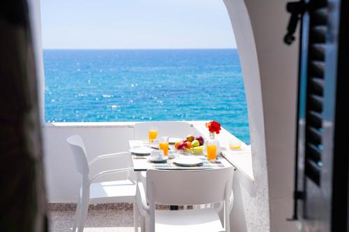 a table with white chairs and a view of the ocean at Kostas Beach Apartments in Agios Gordios