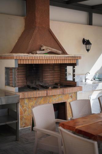 a kitchen with a brick fireplace with a table and chairs at Kostas Beach Apartments in Agios Gordios