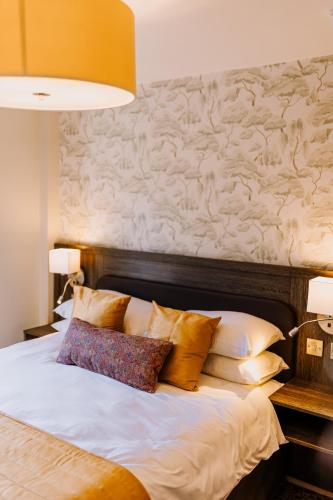 a bedroom with a large bed with pillows on it at The Bull Hotel in Stony Stratford