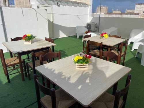 two tables and chairs with flowers on a balcony at "L'Oasi di Favignana" Room and Charme in Favignana