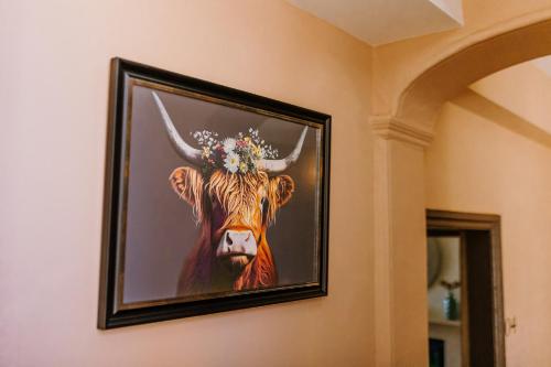 l'immagine di una mucca con una corona di fiori su un muro di The Bull Hotel a Stony Stratford
