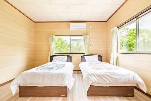 twee bedden in een kamer met houten wanden en ramen bij ウッドペッカーC棟 in Nasu