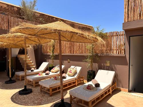een groep stoelen en een parasol op een patio bij Riad Belharra in Marrakesh