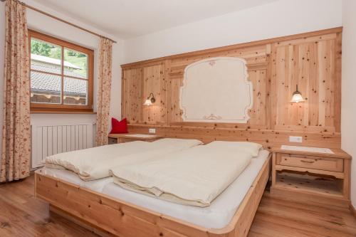sypialnia z dużym łóżkiem i drewnianą ścianą w obiekcie Leishof w mieście Villanders