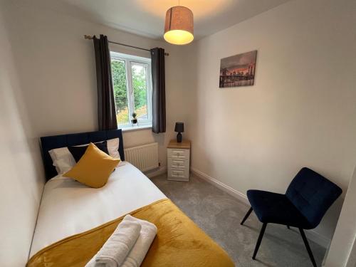 a bedroom with a bed and a chair and a window at The Heathers - Spacious 3 Bed, Home from Home in Burton in Burton upon Trent