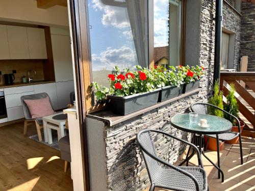 un balcón con una mesa y flores en una ventana en BERUŠKA Apartmán, en Oščadnica