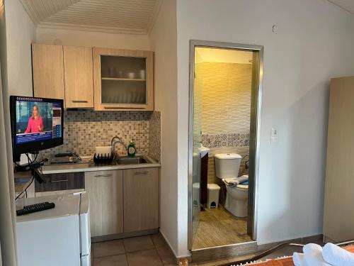 a kitchen with a tv on a counter and a toilet at Apartment & Studios Haido in Vourvourou