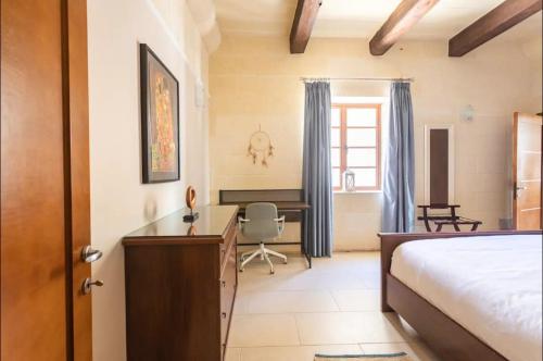 1 dormitorio con cama, escritorio y silla en Inzolia - Peaceful Villa with Pool, en Il-Pergla