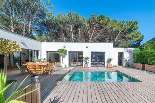 une maison avec une piscine et une terrasse en bois dans l'établissement Villa haut de gamme 160 M2 Piscine chfé et Jacuzzi, à Aigues-Mortes