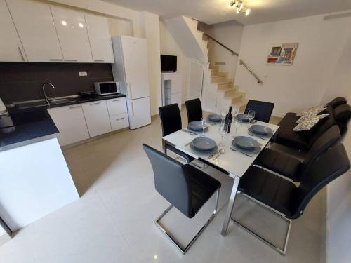 a dining room table with black chairs and a kitchen at Orange Tree House in Šipanska Luka