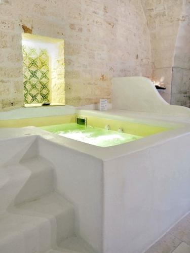 a white bathroom with a sink and a window at Masseria Parco della Grava in Pezze di Greco