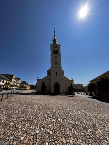 a church with a clock tower on a cobblestone street at Apartmán Kašperák in Kašperské Hory