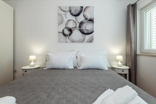 a bedroom with a bed with a painting on the wall at Apartman Enzzo in Šibenik