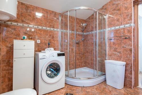 a bathroom with a shower and a washing machine at Apartman Enzzo in Šibenik