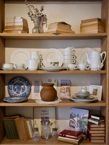 a book shelf filled with plates and cups and dishes at Hostal de la Plaça - Hotel Boutique in Cabrils