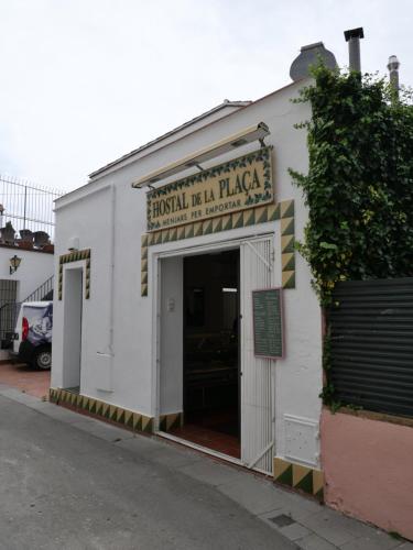 a white building with a doorway with a sign on it at Hostal de la Plaça - Hotel Boutique in Cabrils