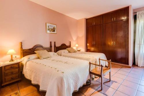 a bedroom with two beds and a chair at Restaurante & Casa Rural Boada in Villamiel