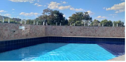 uma grande piscina ao lado de uma parede de tijolos em The Villeneuve Residence em Caldas Novas