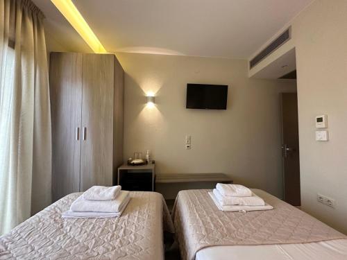 two beds in a room with a tv on the wall at Yulia Luxury Apartments in Ouranoupoli