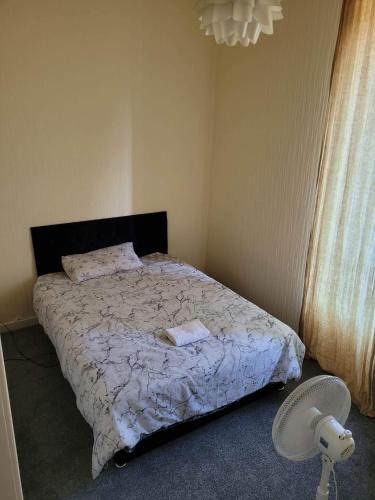 1 dormitorio con 1 cama con edredón blanco y ventilador en Cosy Glasgow Southside Flat en Glasgow