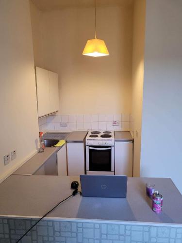 a kitchen with a stove and a laptop on a counter at Cosy Glasgow Southside Flat in Glasgow