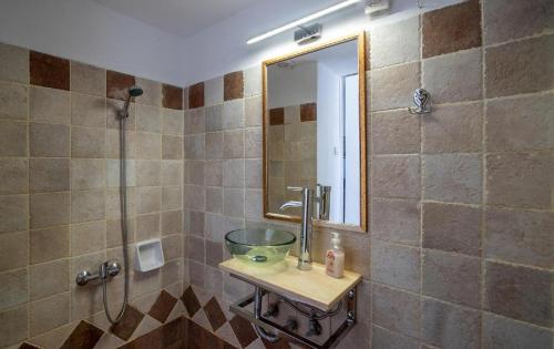 ein Bad mit einem Waschbecken und einer Dusche mit einem Spiegel in der Unterkunft Olga's House in Neon Oitilon