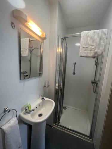 a white bathroom with a sink and a shower at Annie May's Bar, B&B in Skibbereen