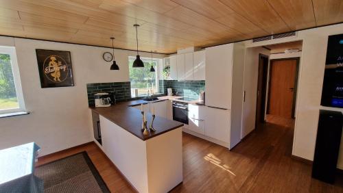 uma cozinha com armários brancos e um tecto de madeira em Hummingenstrand38 em Dannemare