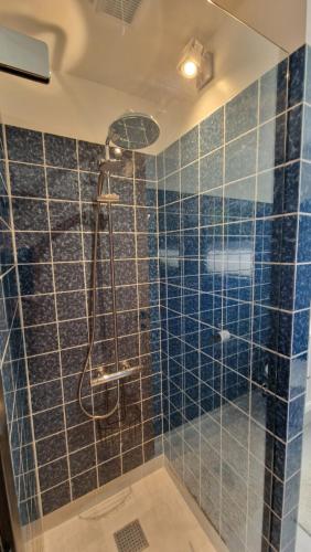 uma casa de banho com um chuveiro com azulejos azuis em Hummingenstrand38 em Dannemare