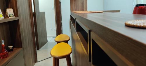 a kitchen with a counter with two yellow stools at Belo Exclusivo AP Com Garagem na Cidade Baixa Próximo a Santa Casa, UFRGS e Centro Histórico - BnB Serviços Inteligentes Por Fioravante in Porto Alegre