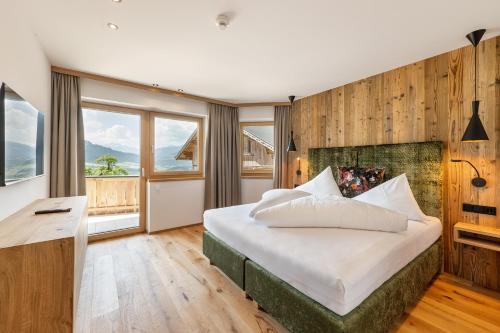 a bedroom with a bed and a desk and windows at Hotel AlpenSchlössl in Söll