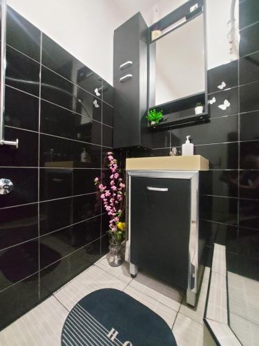 a black bathroom with a sink and a mirror at Pandora's Place in Sarajevo