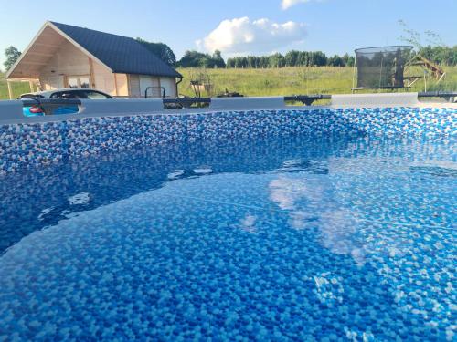 una gran piscina de agua azul con una casa en el fondo en Cuda Wianki en Zdów