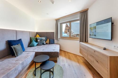 a living room with a couch and a tv at Hotel AlpenSchlössl in Söll