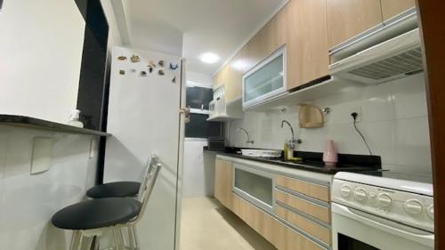 uma pequena cozinha com um frigorífico branco e um banco em Luxuoso a 250 Mts da Praia em Guarapari